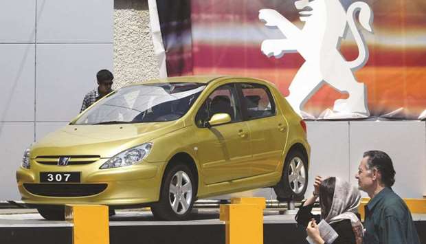 This file photo taken on June 22, 2004 shows an Iranian couple passing by a French Peugeot 307, produced by u201cIran Khodrou201d company, during the annual car fair in Tehran. The EU, led by France, Germany and the UK, has struggled to find a government willing to host the SPV, which risks drawing criticism from the American administration.