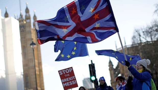 Anti-Brexit activists hold placards and wave Union and EU flags as they demonstrate near the Houses of Parliament in central London