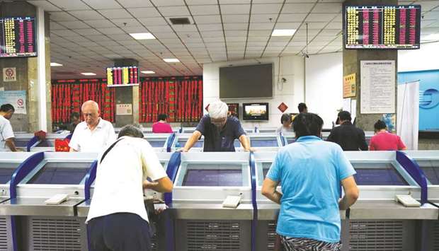 Investors look at computer screens showing stock information at a brokerage house in Shanghai. Chinese stocks shed 0.1% to 2,594.25 points yesterday.