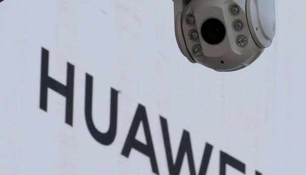 A surveillance camera is seen next to a sign of Huawei outside a shopping mall in Beijing, China