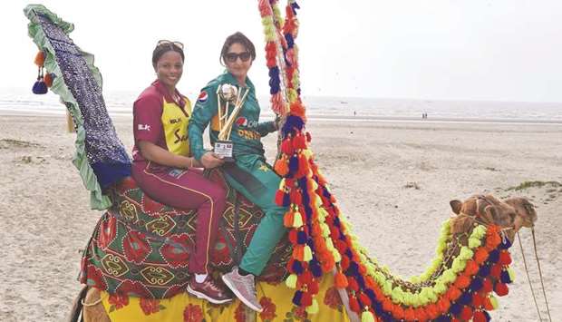 West Indies womenu2019s team captain Merissa Aguilleira (left) and her Pakistan counterpart Bismah Maroof pose with the T20 trophy on a camel in Karachi yesterday. (AFP)