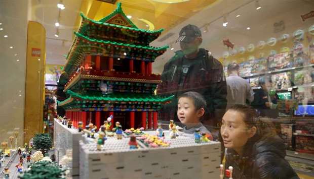 A boy and his mother look at the Zhengyang Gate Tower of Forbidden City made with Lego bricks at a Lego store in Beijing