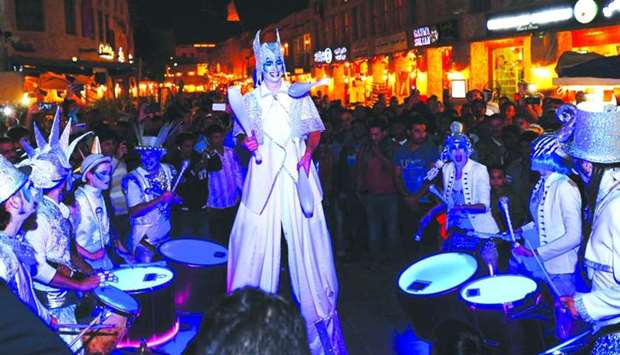 A large crowd gathers around one of the roving performances at the Souq Waqif Spring Festival, which concluded Friday. PICTURE: Ram Chand.