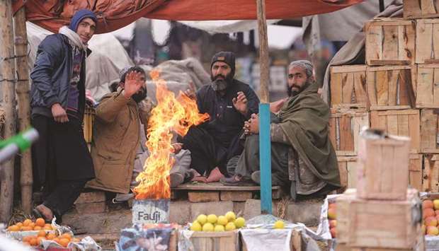 Vendors heat up around a fire at a fruit market during a cold and foggy morning in Islamabad yesterday.