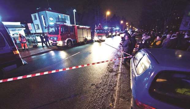 Police and firefighters stand in front of a place, where a fire that broke out in an escape room killed five teenage girls, in the northern Polish city of Koszalin.
