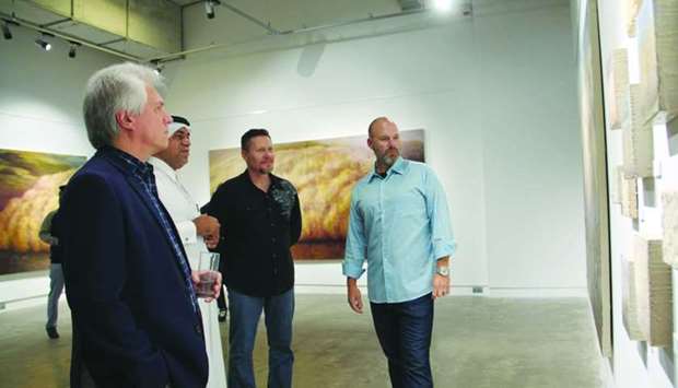 Qatar-based artist Jesse Payne (right) shows his works to Doha Fire Station director Khalifa al-Obaidly and other guests.