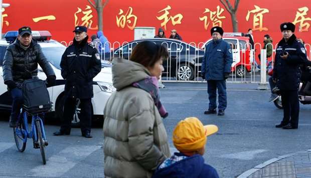 Police watch as a woman and a child leave a primary school that was the scene of a knife attack in Beijing, China. Reuters