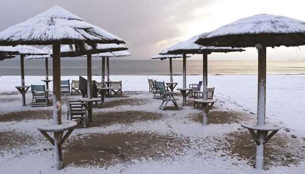 Beach umbrellas are covered with snow in the town of Artemida, Greece, yesterday.