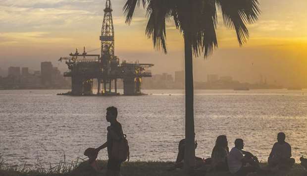 People watch the sunset in front of a Queiroz Galvao SA offshore oil platform in the Guanabara Bay near Niteroi, Rio de Janeiro state, Brazil (file).