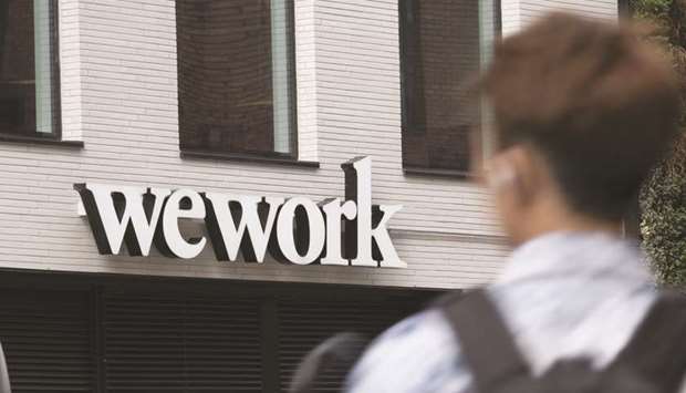 A pedestrian walks past a logo for WeWork the co-working office space, operated by the parent company We Co, on City Road in London. New leases by the flexible office firm nosedived in New York and London, its top two markets, in the final quarter of last year, CoStar Group Inc data show.