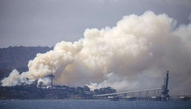 Smoke rises from the Eden Woodchip Mill, from a fire that has been blazing for days, after bushfires came close the previous week to Eden, Australia, yesterday.