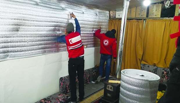 QRCS personnel installing thermal insulation inside the tents of Syrian refugees in Lebanon.