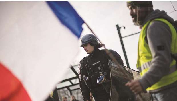 A u2018yellow vestu2019 demonstrator holds the French flag during a protest in Nantes, western France, as part of a nationwide multi-sector strike against the French governmentu2019s pensions overhaul.