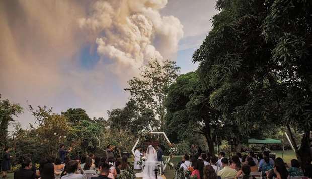 Chino and Kat Palomar attend their wedding ceremony as Taal Volcano sends out a column of ash in the background in Alfonso, Cavite, Philippines on January 12. Randolf Evan Photography/Facebook