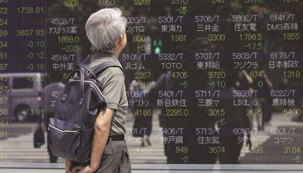 A pedestrian looks at an electronic stock board outside a securities firm in Tokyo. Japanese shares were among the biggest gainers yesterday, rising 0.7% to 24,025.17 as the dollar advanced against the yen owing to a rush out of safety u2013 giving a boost to Japanu2019s exporters.