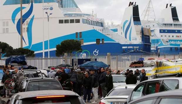 Ferry passengers stand in front of a boarding gate at the port of Marseille, blocked by French CGT dock workers on strike during the 42nd consecutive day of strikes against French government's pensions reform plans in France