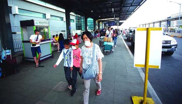 People wearing face masks arrive at the Ninoy Aquino International Airport Terminal 3 in Manila on January 13. All departing and arriving international and domestic flights were suspended on January 12 u201cdue to volcanic ash in the vicinity of the airportu201d and nearby air routes, the Civil Aviation Authority of the Philippines said.