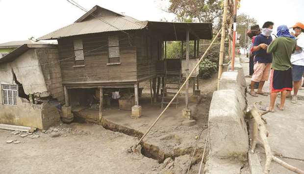 Residents look at a neighbouru2019s house standing on a fissure, caused by tremors caused by Taal volcanou2019s activity, in Lemery town, Batangas province, south of Manila.