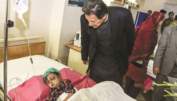 Pakistanu2019s Prime Minister Imran Khan looks at a young injured avalanche victim at a military hospital in Muzaffarabad yesterday.