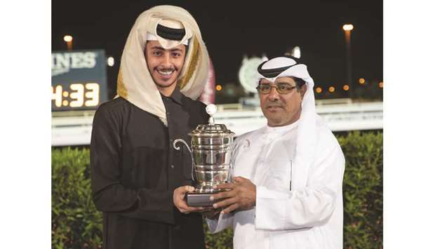 QREC deputy chief steward Abdulla al-Kubaisi (right) presents the owneru2019s trophy to Injaaz Stud representative Khalifa bin Sheail al-Kuwari after Izzthatright won the Muaither Cup at Al Rayyan Park yesterday. PICTURES: Juhaim