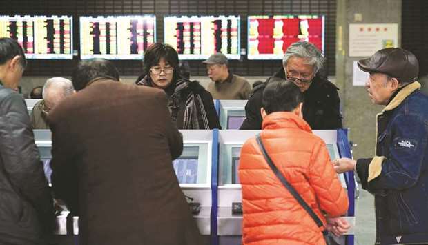Investors look at computer screens showing stock information at a brokerage house in Shanghai yesterday.