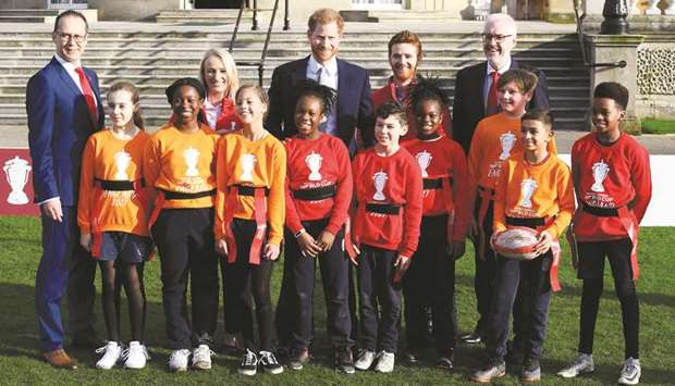 Prince Harry poses for a group photo with Rugby League World Cup 2021 ambassadors Jody Cunningham and James Simpson and local school children during a rugby event at Buckingham Palace gardens in London yesterday.