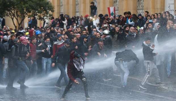 Demonstrators are hit by water canon during a protest against a ruling elite accused of steering Lebanon towards economic crisis in Beirut, Lebanon