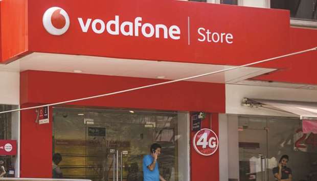 Customers talk on mobile phones outside a Vodafone India store in New Delhi. Franklin Templeton Asset Management (India) marked down its debt exposure to Vodafone Groupu2019s India venture to zero, concerned by the operator having to pay $4bn in back-fees as early as next week.