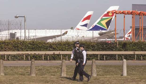 Police walk around the perimeter fence against a backdrop of passenger aircraft, operated by British Airways and South African Airways at London Heathrow Airport (file). Loss-making SAA has already burned through a loan it got from banks last month, according to people familiar with the matter.