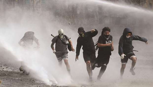 Demonstrators are sprayed with a water cannon by riot police during anti-government protests in Santiago.