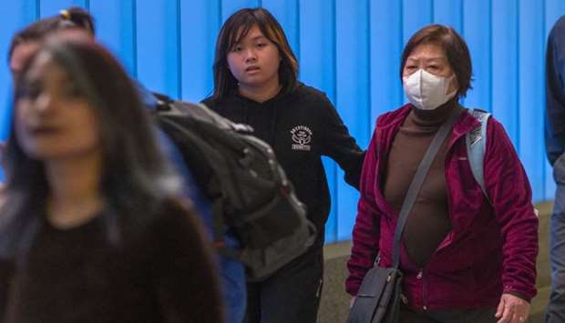 A woman arriving on an international flight to Los Angeles International Airport wears a mask on the first day of health screenings for coronavirus of travelers from Wuhan, China