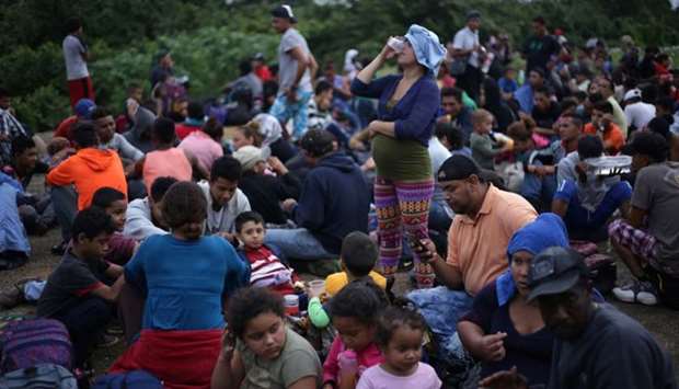 Migrants from Central America, part of a caravan travelling to the US, wait to cross into Mexico at the border between Guatemala and Mexico, in El Ceibo, Guatemala, on Saturday