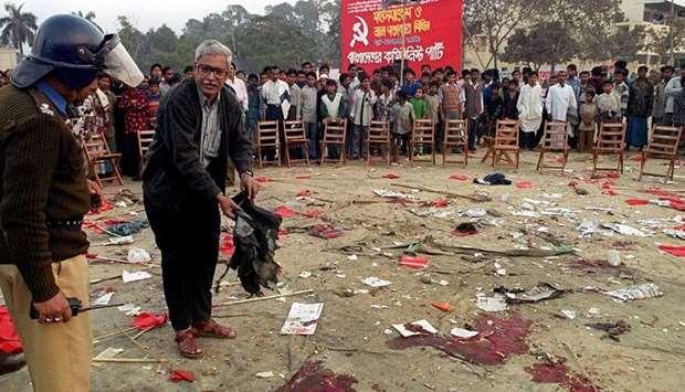 In this file photo taken on January 20, 2001, an unidentified leader of the Bangladesh Communist Party (BCP) shows a policeman (L) at the blast site of the bomb that went off during a BCP rally in Dhaka.