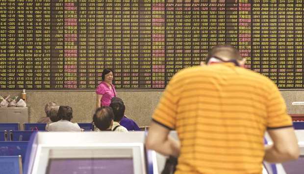 An investor stands at a trading terminal in front of an electronic stock board at a securities brokerage in Shanghai. The bourse gained 0.7% to 3,095.79 points yesterday.