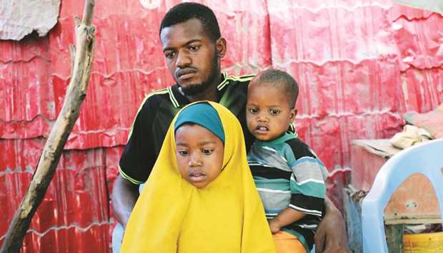 Somali farmer Abdi Abukar Hassan and father of Mohamed Abdul, who was injured in the car bomb attack at the Afgoye junction, sits with his son Sadak Abdi and daughter Khadija Abdi, during a Reuters interview outside his house in Mogadishu, yesterday.
