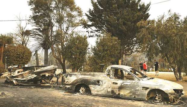 Vehicles gutted by bushfires are seen in the town of Lake Conjola in New South Wales yesterday.