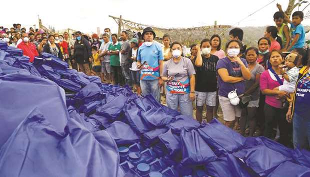 Residents, who refuse to evacuate, queue for relief goods following Taal volcanou2019s eruption, in Talisay, Batangas, yesterday.