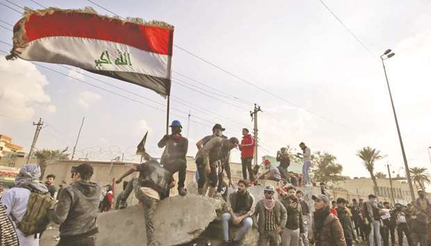 Iraqi protesters wave the national flag amid clashes with riot police following a demonstration at Baghdadu2019s Tayaran Square, east of Tahrir Square, yesterday.