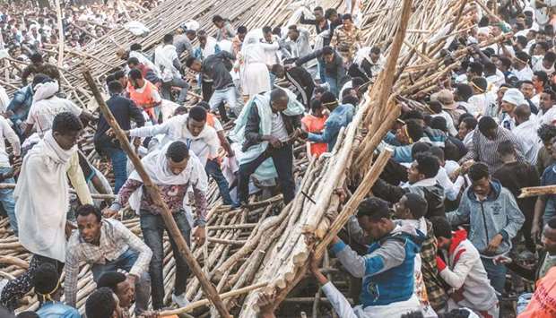 A crowd removes scaffoldings of a structure that collapsed, trapping and injuring dozens of people, during the celebration of Timkat, the Ethiopian Epiphany, in Gondar, yesterday.