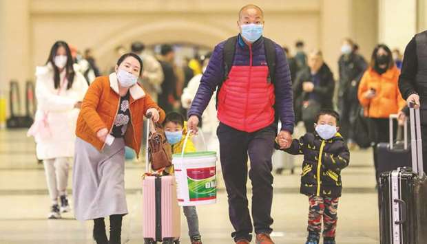Commuters wearing face masks walk in Hankou railway station in Wuhan, in Chinau2019s central Hubei province yesterday.