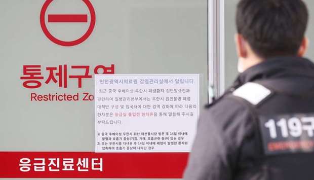 A rescue worker walks past a notice about new coronavirus that has broken out in China, at a hospital where a Chinese woman, who flew from Wuhan, China, and has been confirmed its first case of a new coronavirus, is isolated, in Incheon, South Korea