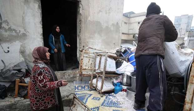 Umm Hatem (L), a Syrian woman displaced from Maar Shamshah town in the eastern countryside of Maaret al-Numan, helps unload her belongings at a makeshift camp in Idlib in northwestern Syria on December 31, 2019.