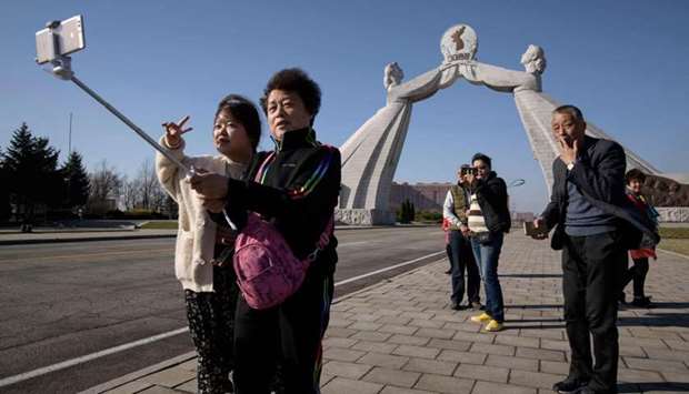 Tourists from China pose for photos before the Three Charters monument in Pyongyang on April 15, 2019. North Korea will ban foreign tourists to protect itself against a new SARS-like virus that has claimed at least nine lives in China and sickened hundreds, a major tour operator said Wednesday.