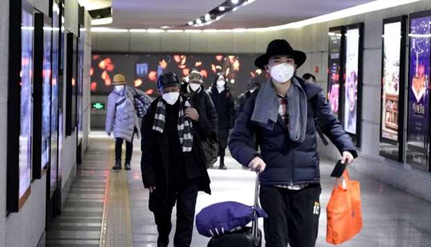 People wearing masks walk through an underground passage to the subway in Beijing yesterday