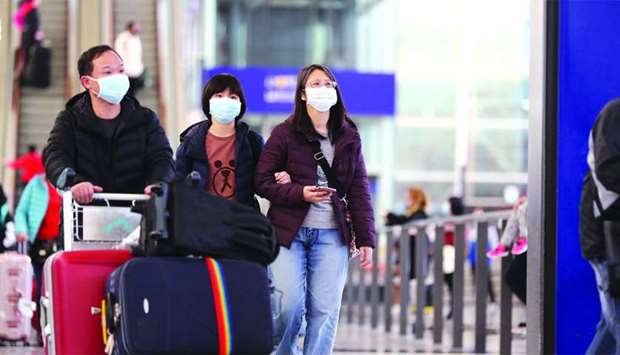 Travellers wearing face masks walk through the arrival hall at the Hong Kong International Airport