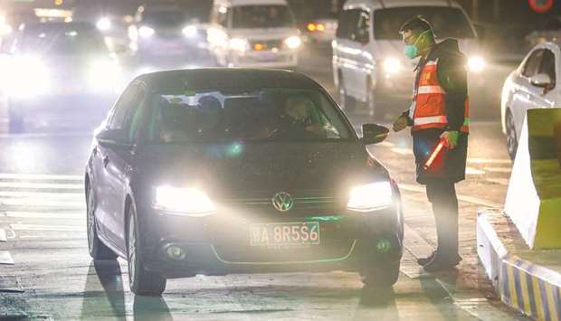 A staff member talks with a driver as he checks body temperature of passengers at an exit of a highway in Wuhan, in Chinau2019s central Hubei province on January 21.