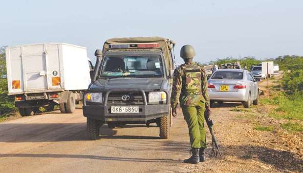 A Kenyan police officer observes traffic near the scene where armed assailants killed three people and injured two others in Nyongoro area of Lamu County yesterday.