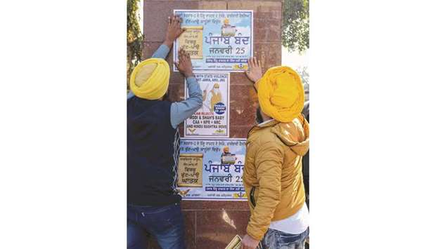 Activists of the Dal Khalsa Sikh organisation stick posters on a wall asking for a strike to protest against the new citizenship law, in Amritsar, Punjab yesterday.