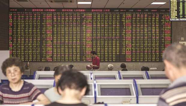 Investors stand at trading terminals in front of an electronic stock board at a brokerage in Shanghai.