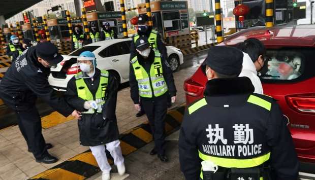 Police officers wearing masks check the boot of a car for smuggled wild animals following the outbreak of a new coronavirus, at an expressway toll station on the eve of the Chinese Lunar New Year celebrations, in Xianning, a city bordering Wuhan to the north, Hubei province, China